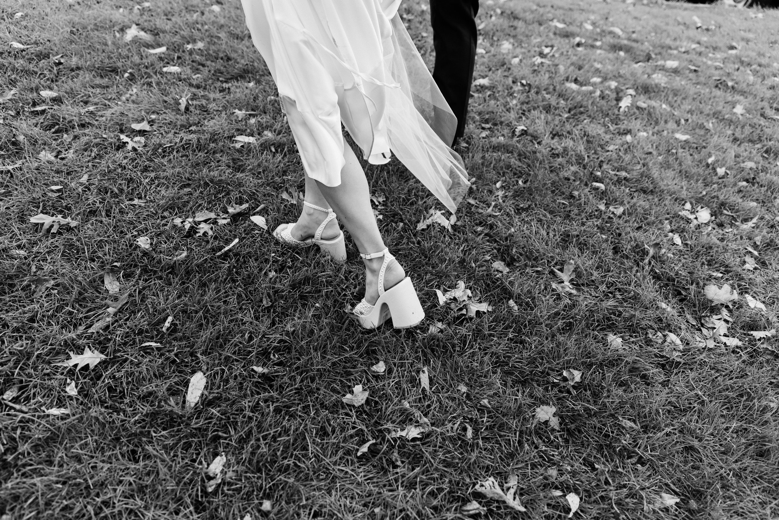 Close up of bride and groom feet walking through Fall leaves