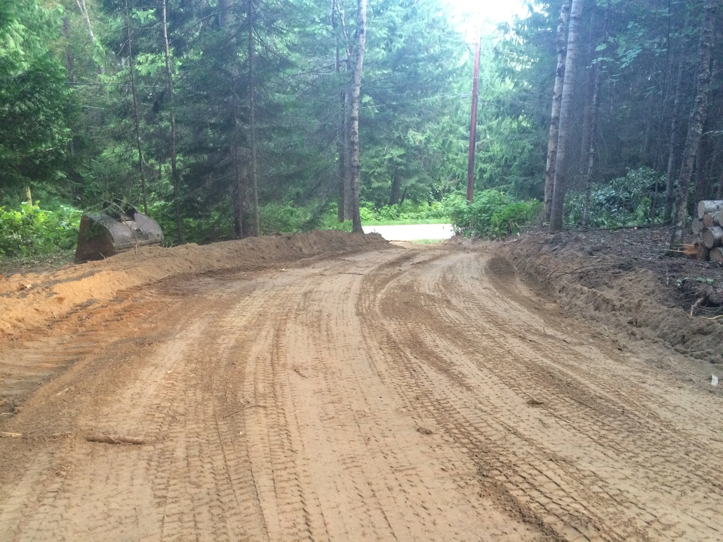 NEW RESIDENTIAL DRIVEWAY trees cleared and roughed in and compacted sub-grade c/w with slope for drainage and ditching