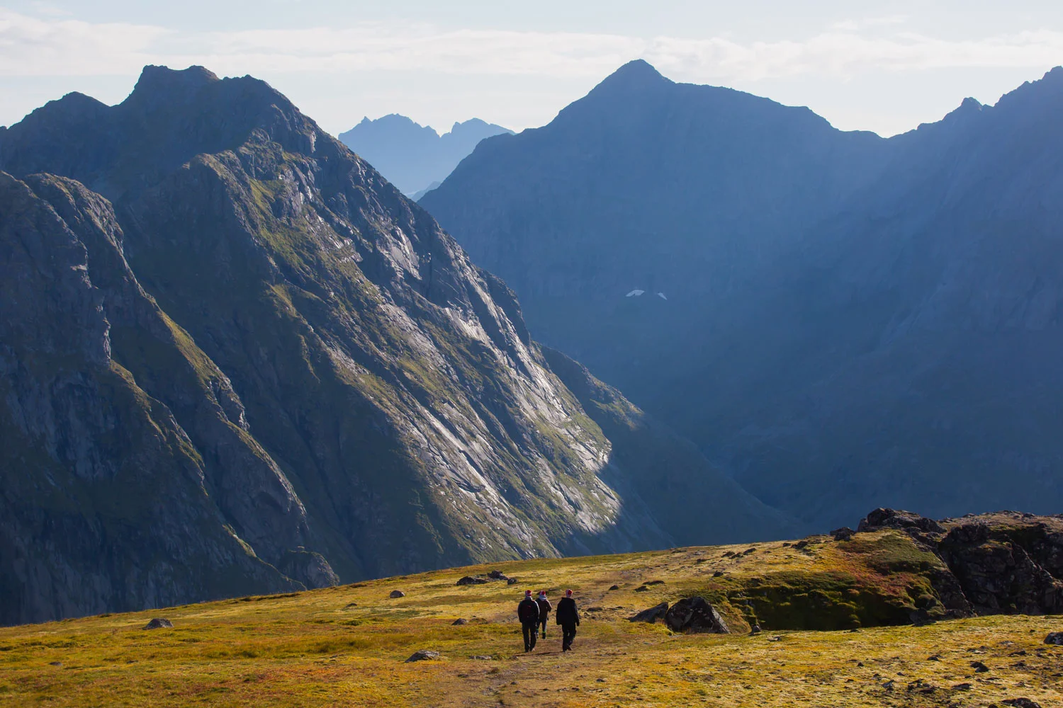 Beautiful Vibrant Norwegian Mountain Landscape from Ryten peak - famous mountain in Lofoten Islands, Moskenes municipality, Nordland with a view of Kvalvika beach, with hiking tourists and blue sky. Those soaring landscapes looked daunting from afar but have been made accessible by a network of trails