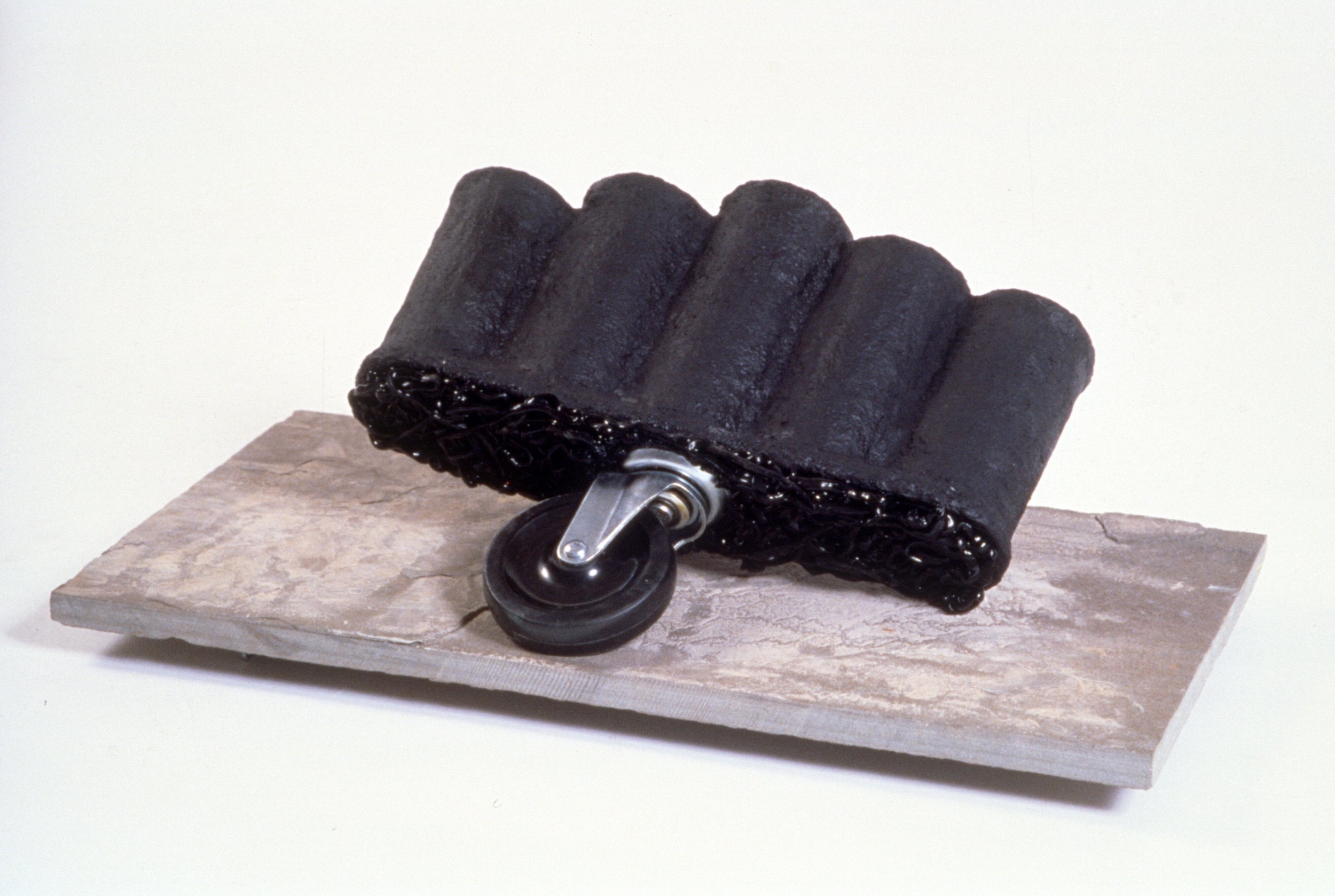 Two-Wheeler materials include; found objects, paper mache, silicone, wheel, acrylic paint, copper tubing on slate base 30 x 34 x 24 inches 1988