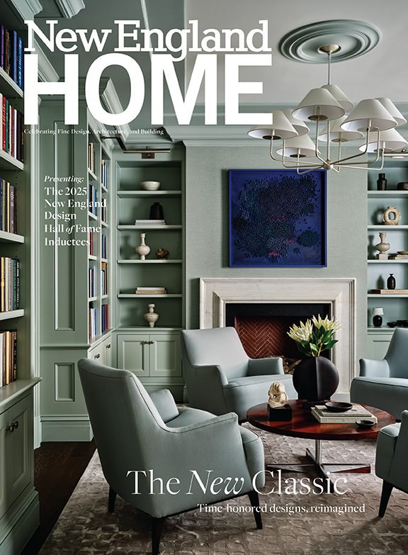 Cover of New England Home magazine featuring a sophisticated living room with pastel green walls, built-in bookshelves, tufted chairs, a fireplace with a white mantel, a dark wood coffee table with a vase of flowers, and a modern chandelier.