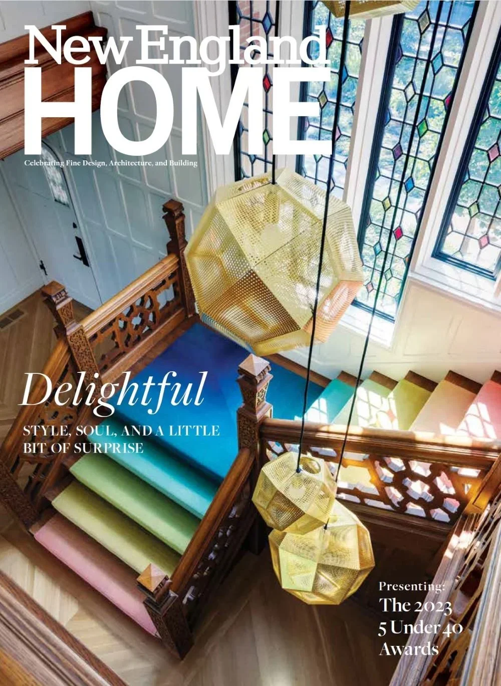 Colorful staircase with rainbow-colored steps, wooden railing with intricate carvings, stained glass windows, and modern hanging gold pendant lights in a house interior.