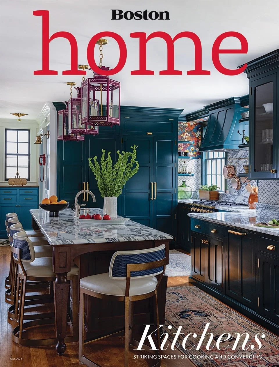 A colorful kitchen with dark blue cabinets, a marble island, and a patterned backsplash, featuring decorative elements and greenery.