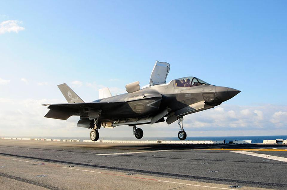 A Marine F-35B fighter lifts off from the deck of the amphibious assault ship USS Wasp. The open hatch behind the cockpit enables air to flow through a mid-fuselage lift fan; that plus downward-vectored engine nozzles at the rear give the plane vertical lift so it can land pretty much anywhere. Image from Wikimedia