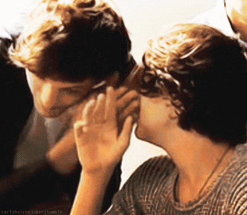 An animated gif of a very young Harry whispering in Louis’s ear.