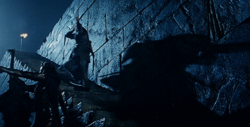 An animated gif of Legolas, from the Lord of the Rings movies, using a shield to surf down a staircase while shooting enemies with a bow.