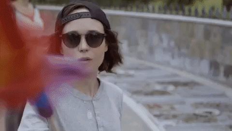 An animated gif of Ellen Page waving a rainbow flag.