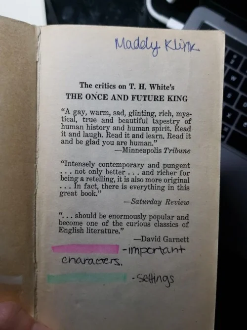 An old paperback copy of T.H. White’s The Once and Future King , open to the front matter (laudatory quotes). The name “Maddy Klink” is written in a childish hand in the top right corner. A key is drawn in the blank space at the bottom of the page: pink highlighting denotes important characters, and green highlighting denotes settings.