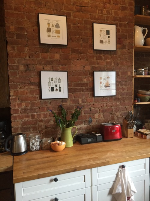 Four adorable fanart images representing the four Harry Potter houses, hanging on Elizabeth’s brick kitchen wall.