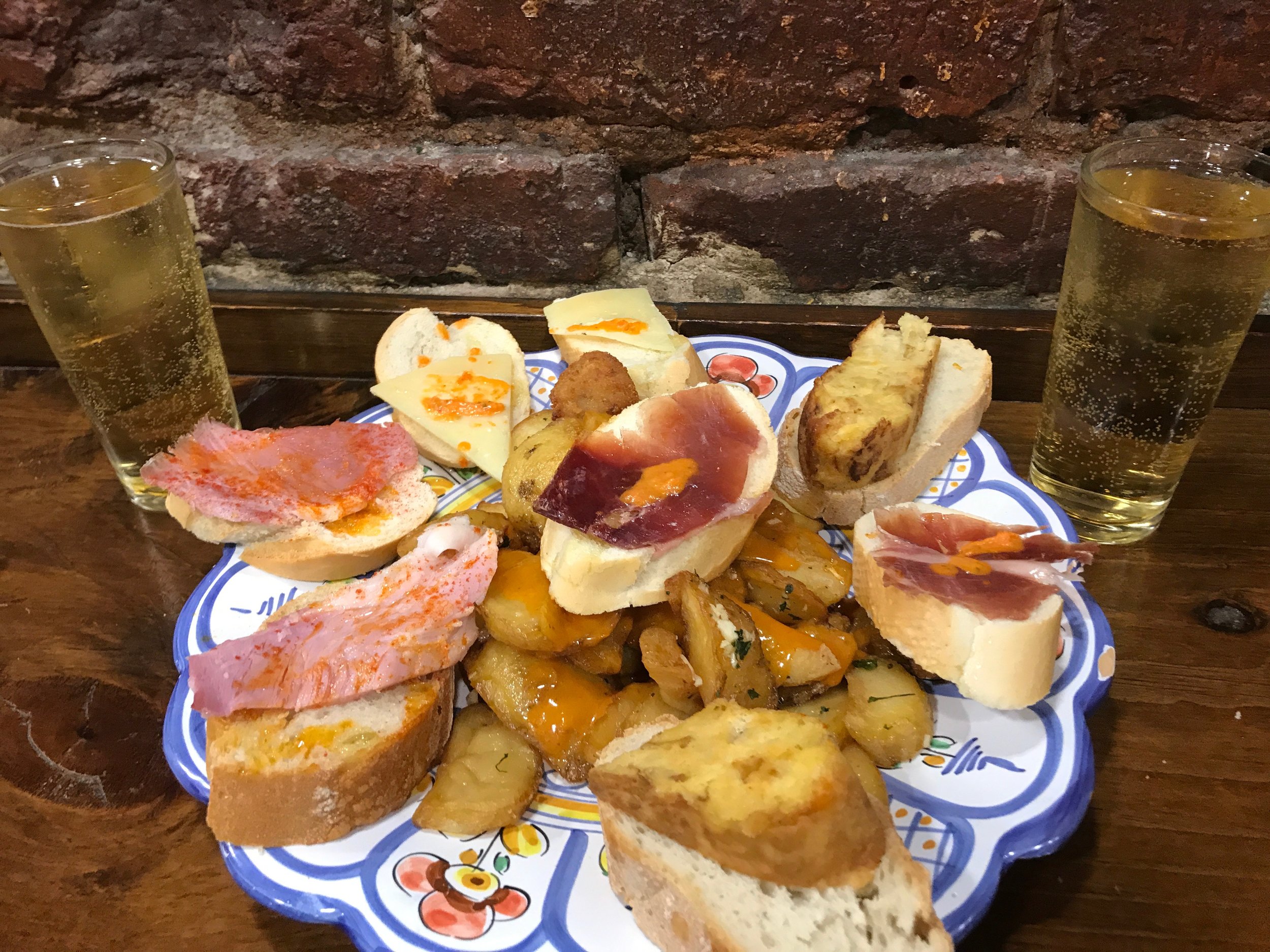 A selection of tapas. The patatas bravas are the potatoes covered in hotsauce at the bottom.