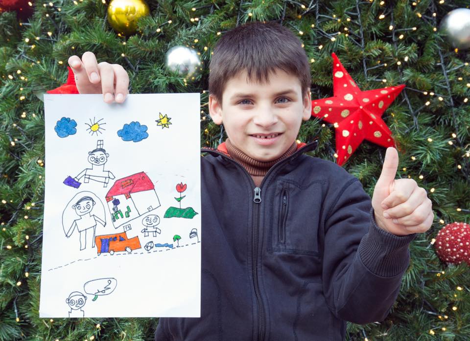 Muhamed Al Kadad, 8, Síria “Esta é a minha casa, os meus fihos estão a brincar enquanto eu volto do trabalho com a minha mala. Eu quero ser médico quando crescer. Feliz Natal para todos”. Muhamed gosta muito de traços coloridos. Mora com seus tr