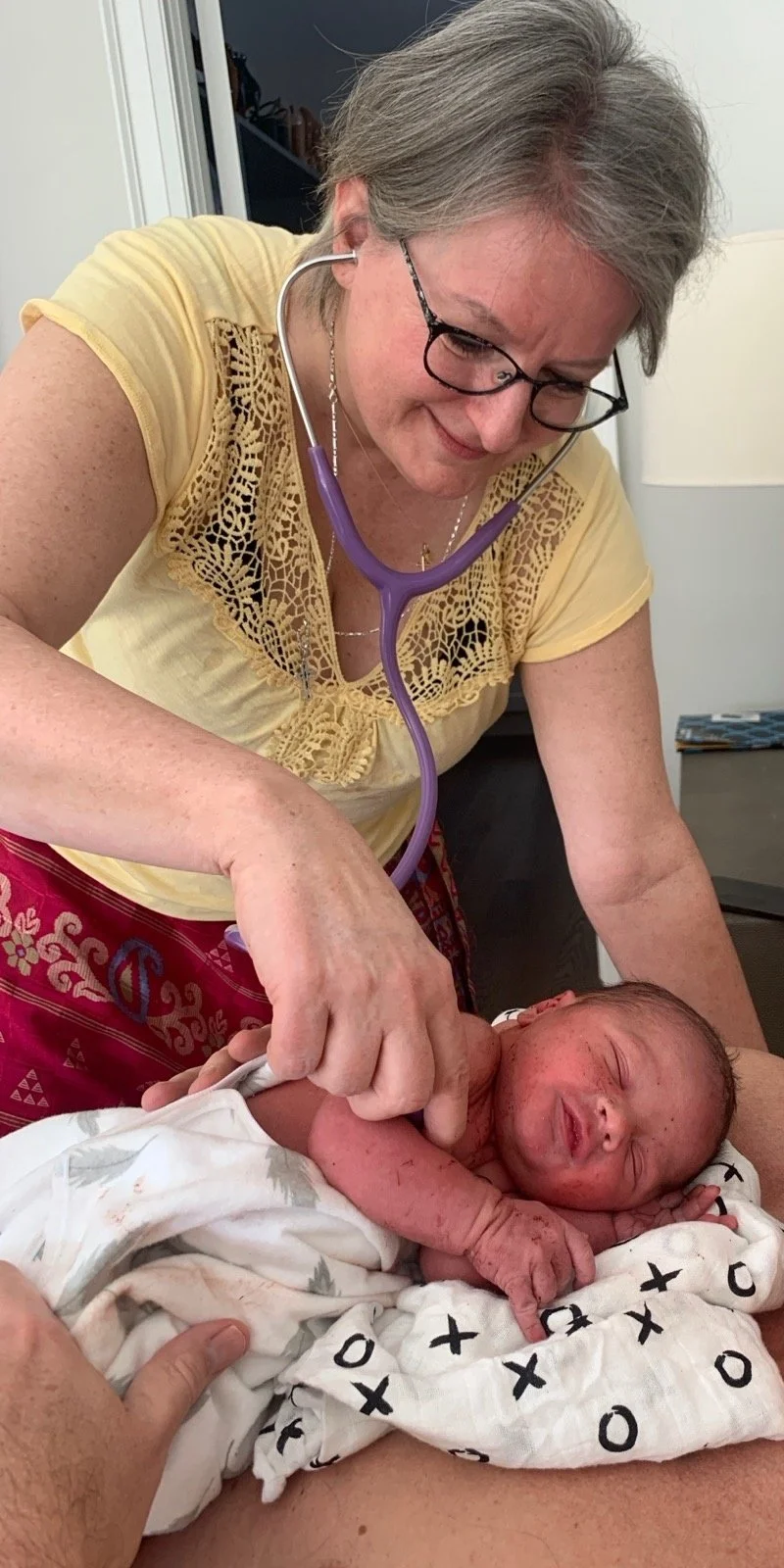Billie Harrigan listening to a newborn's heart with a stethoscope during a home visit