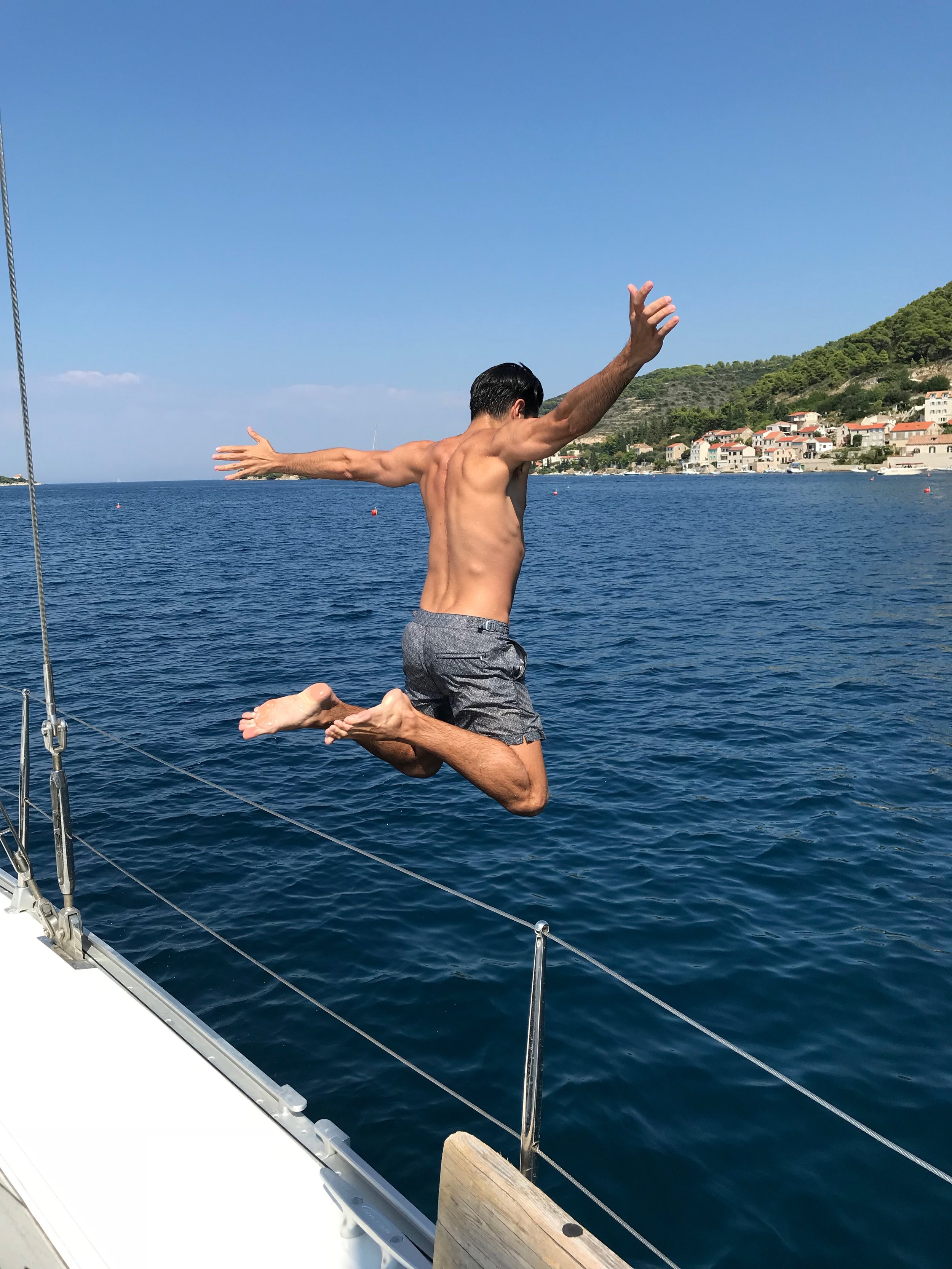 Designer jumping off boat into sea