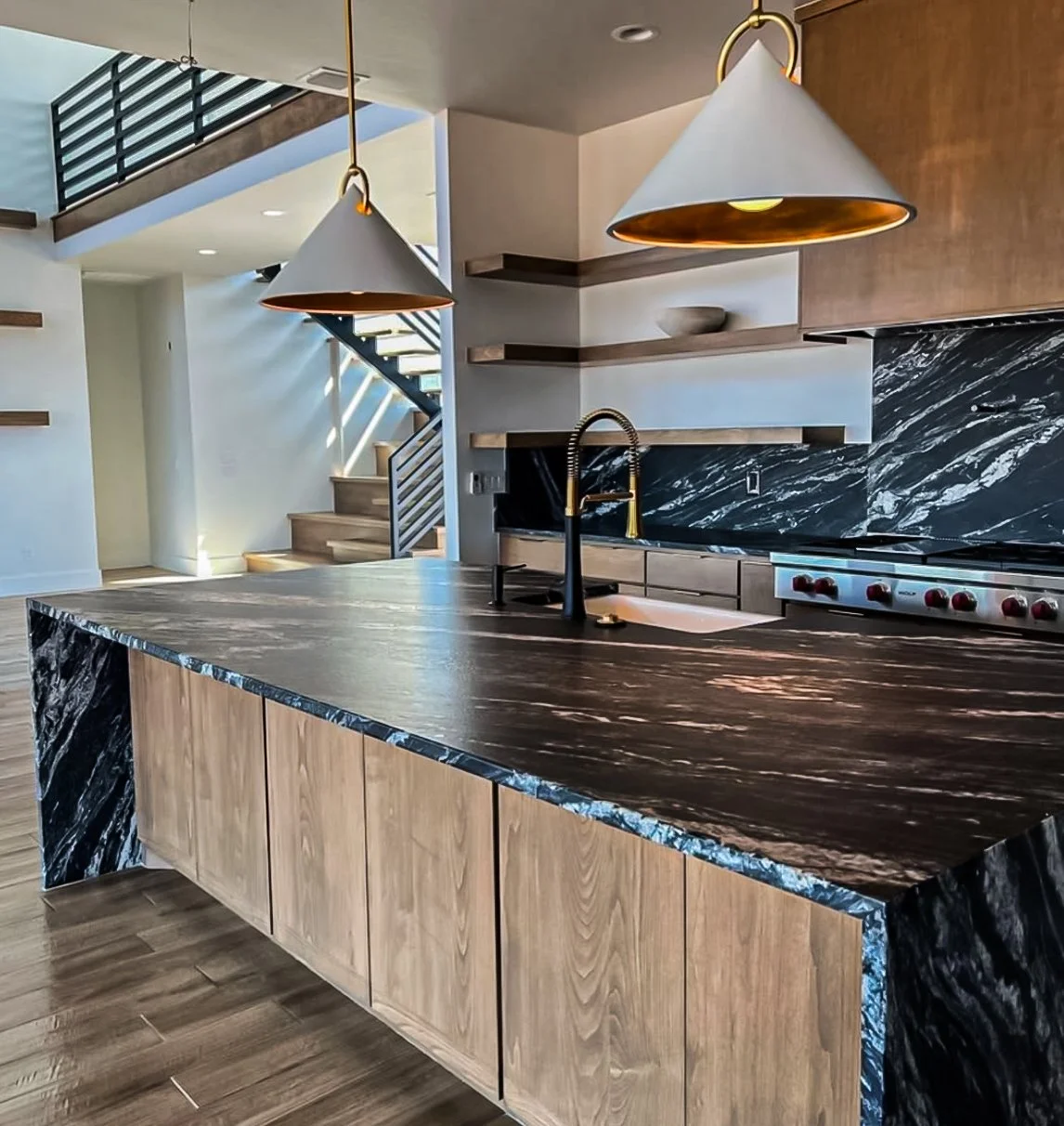 Modern kitchen with black marble waterfall island, gold pendant lighting, and walnut cabinetry by Kara Legako Design, Dallas TX