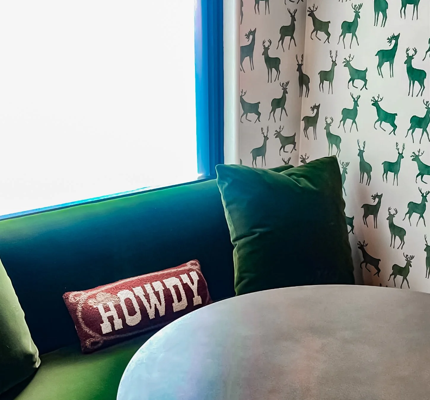 Playful breakfast nook with green velvet banquette, deer print wallpaper, and Howdy pillow by Kara Legako Design, Dallas TX