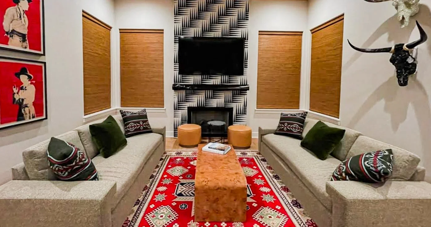 Symmetrical Western-inspired living room with red kilim rug, cowboy pop art, geometric fireplace wallpaper, and longhorn decor by Kara Legako Design, Dallas TX