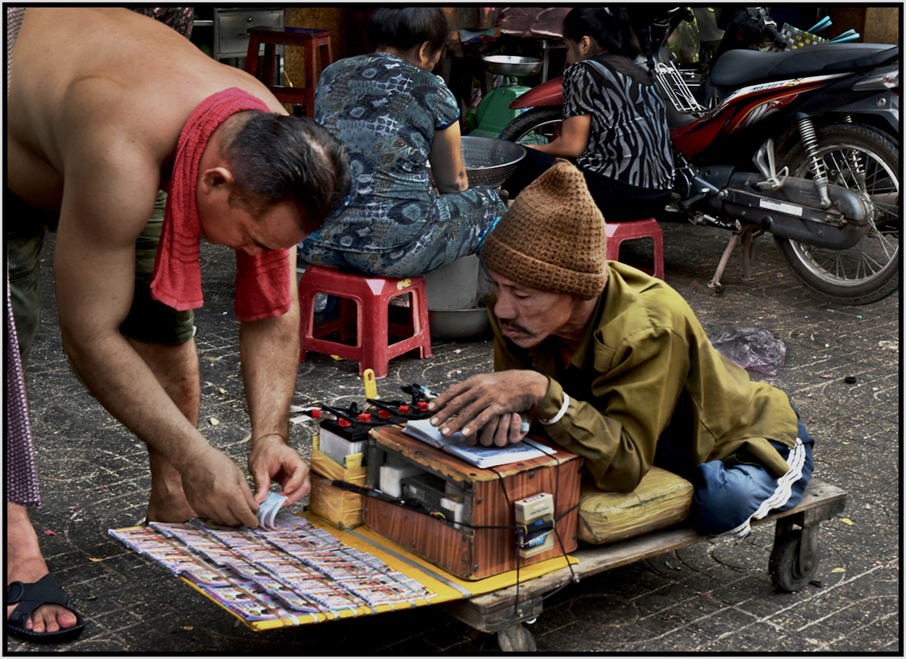  Man with no legs sells lottery tickets amidst vendors at the Binh Tay Market, Cholon, Saigon/HCMC, Dec. 2015. #3848 