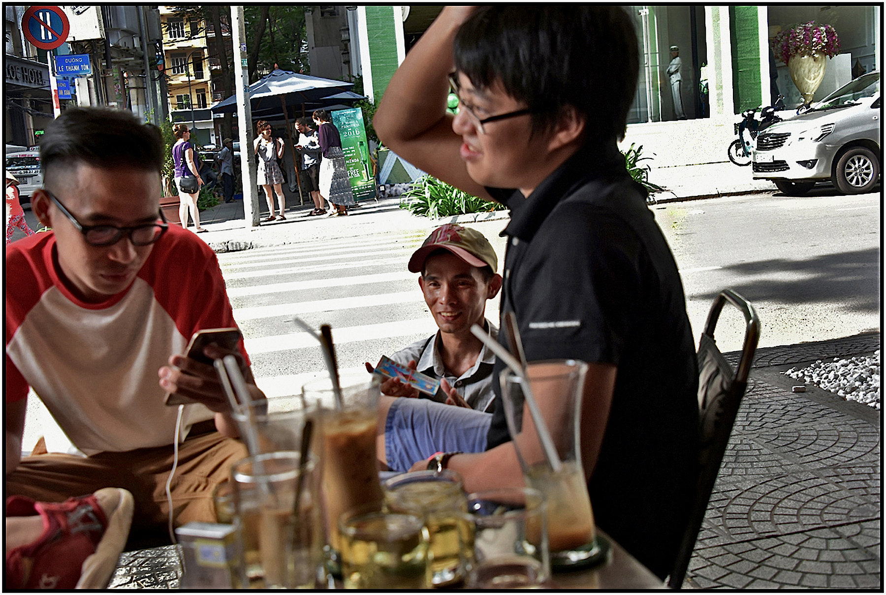  Four teenage boys at a Coffee Cafe as a legless man attempts to sell lottery tickets. Saigon/HCMC, Jan. 2016. #0155 