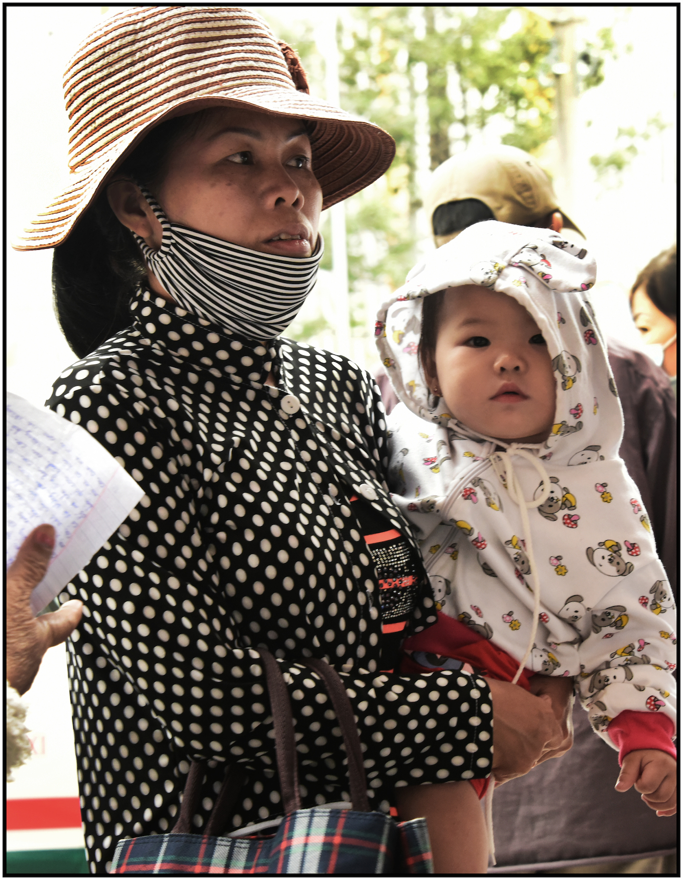  Woman with child wait outside Binh Tay Market, for merchendise she purchased, to be delivered to her vehicle, Binh Tay Market, Cholon, Saigon/HCMC, Dec. 2015 
