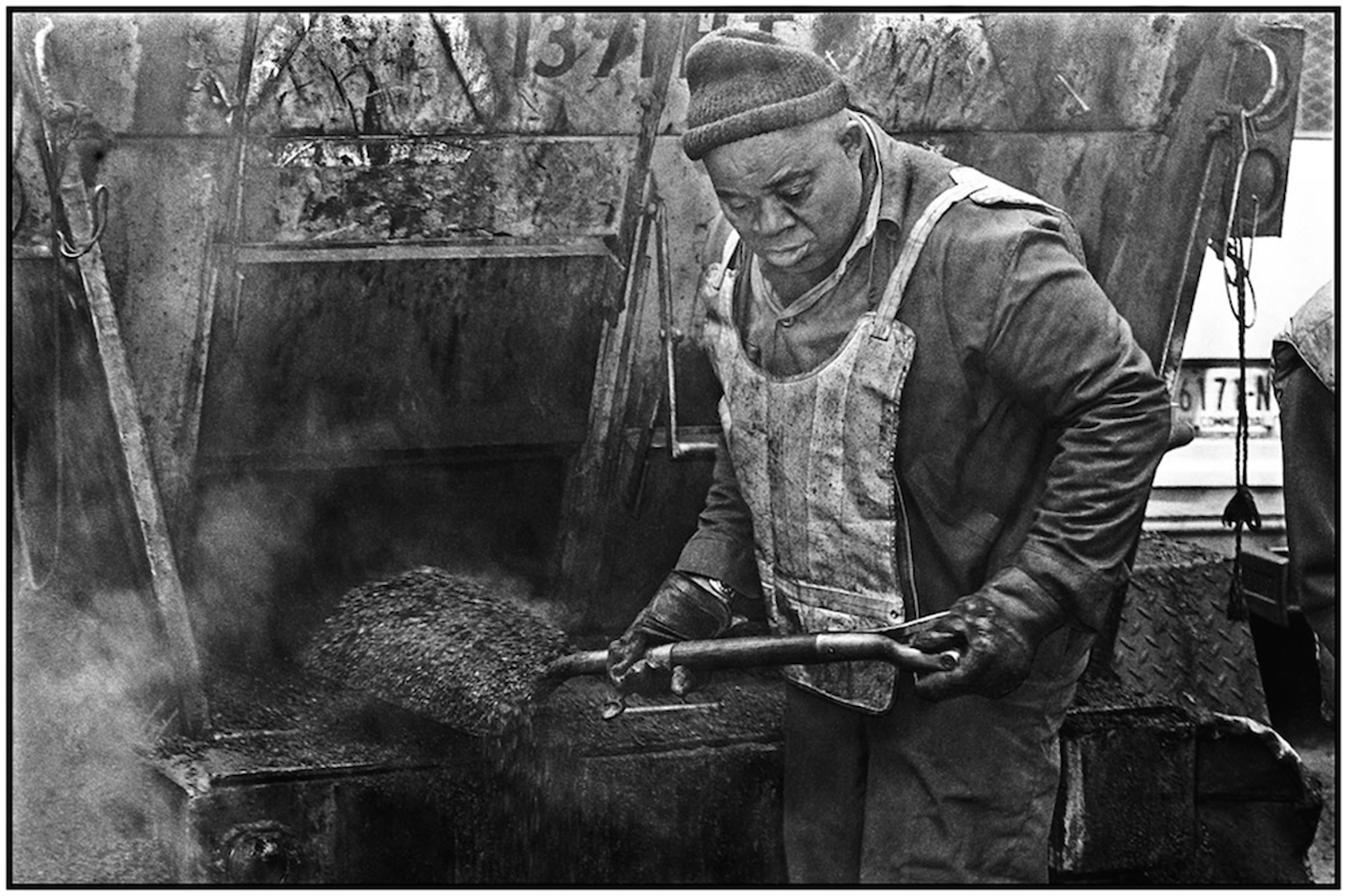   Highway Repairer Chester Bailey shovels hot asphalt to fill pothole in midtown Manhattan. 1984.  