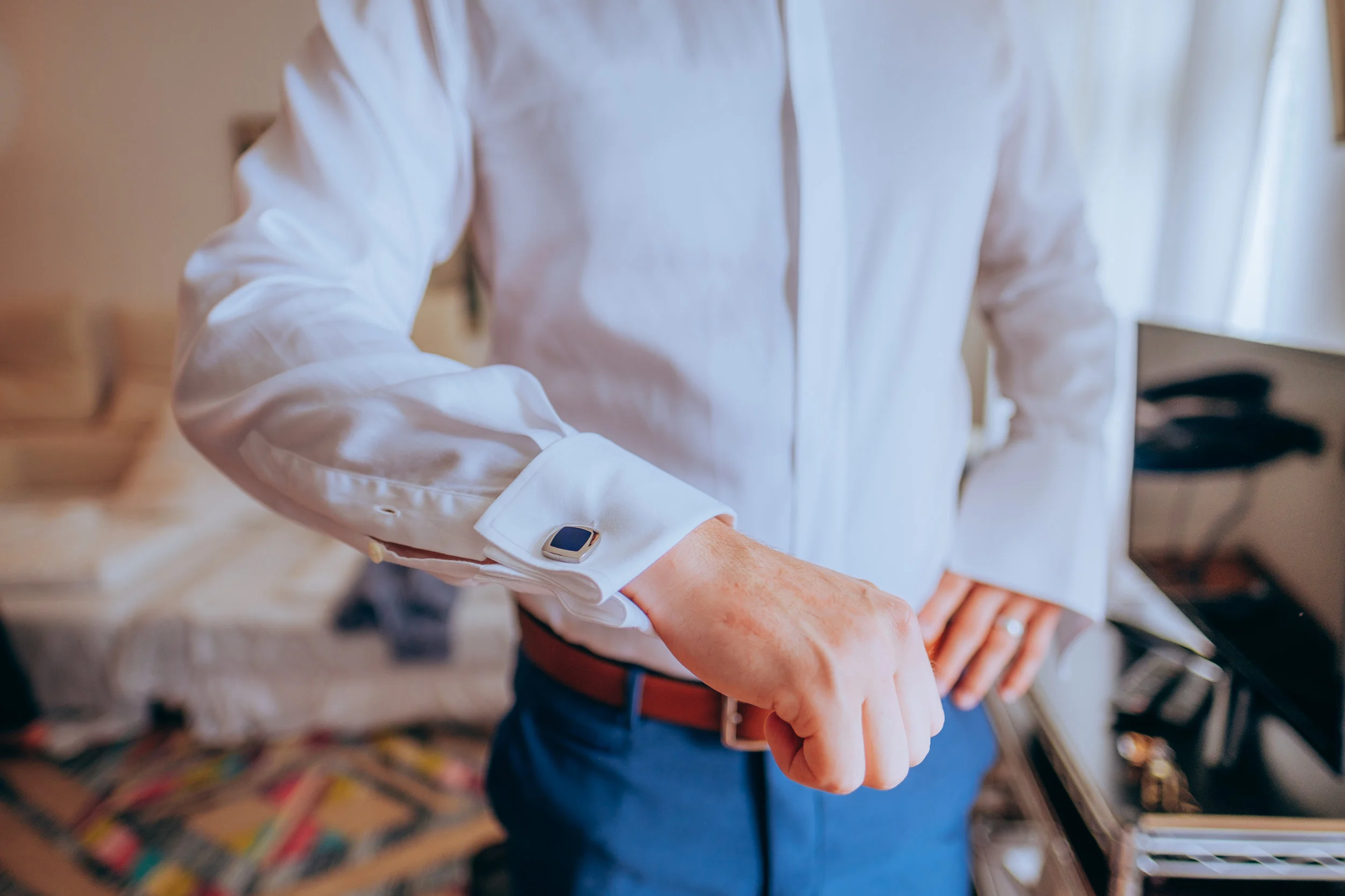 Eine Person in einem weißen Hemd überprüft eine Smartwatch am Handgelenk in einem Raum mit Büchernregalen.
