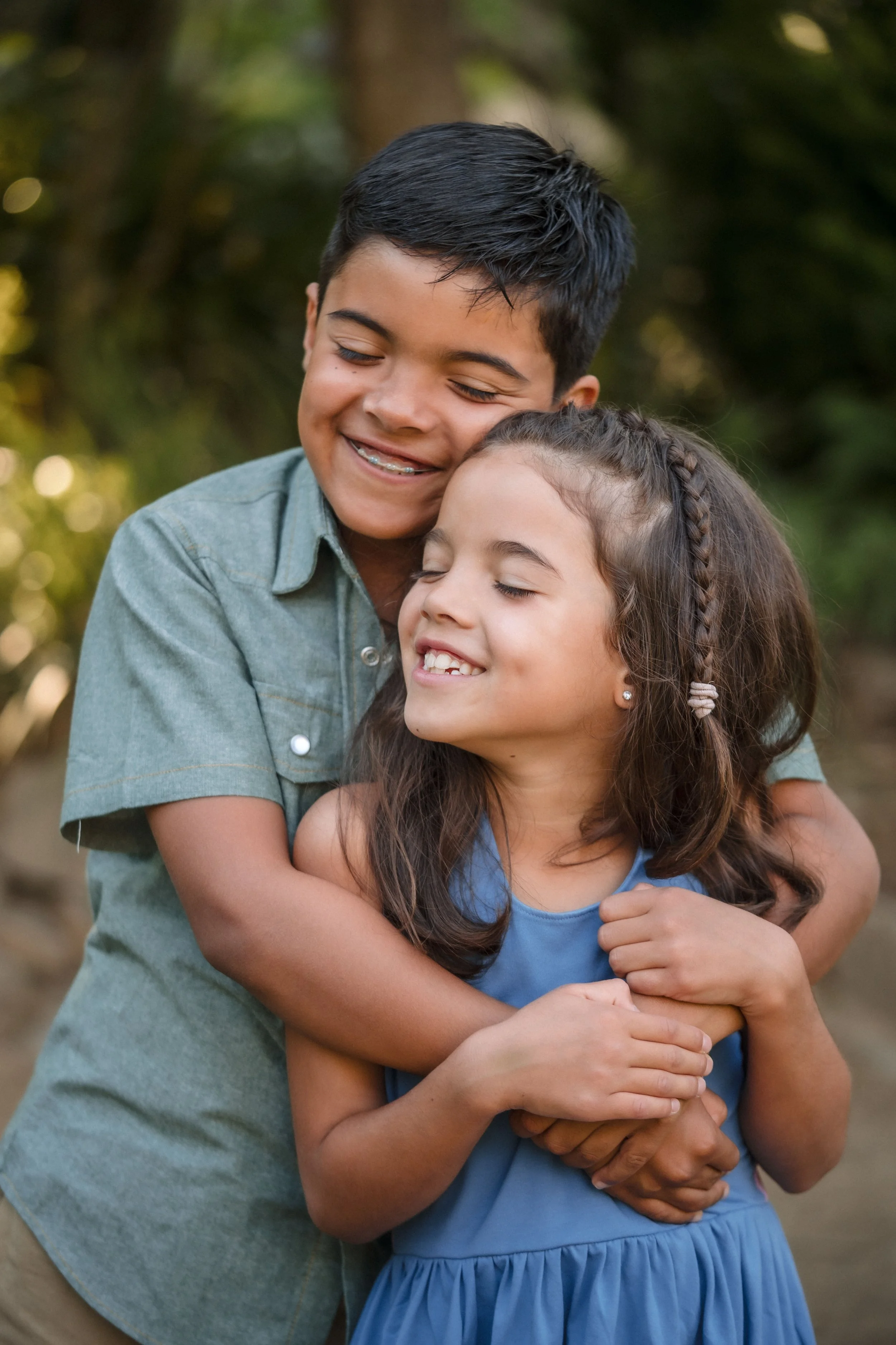 A boy and girl hug each other outdoors, both smiling with their eyes closed while taking family photos with Sacramento family photographer, Katherine Nicole Photography.