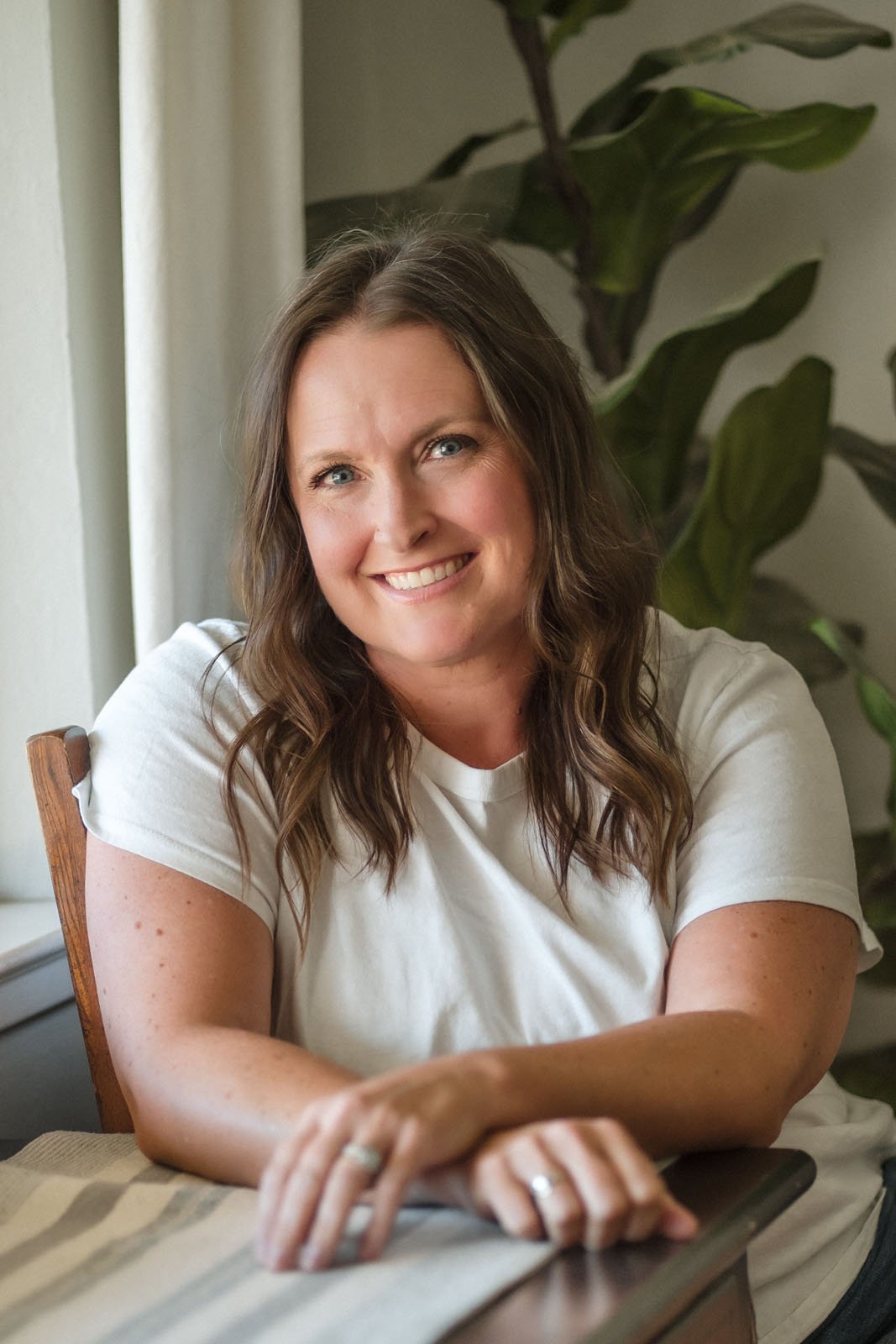 Northern California elopement photographer Katie Moeller,  smiles at the camera, sitting a table