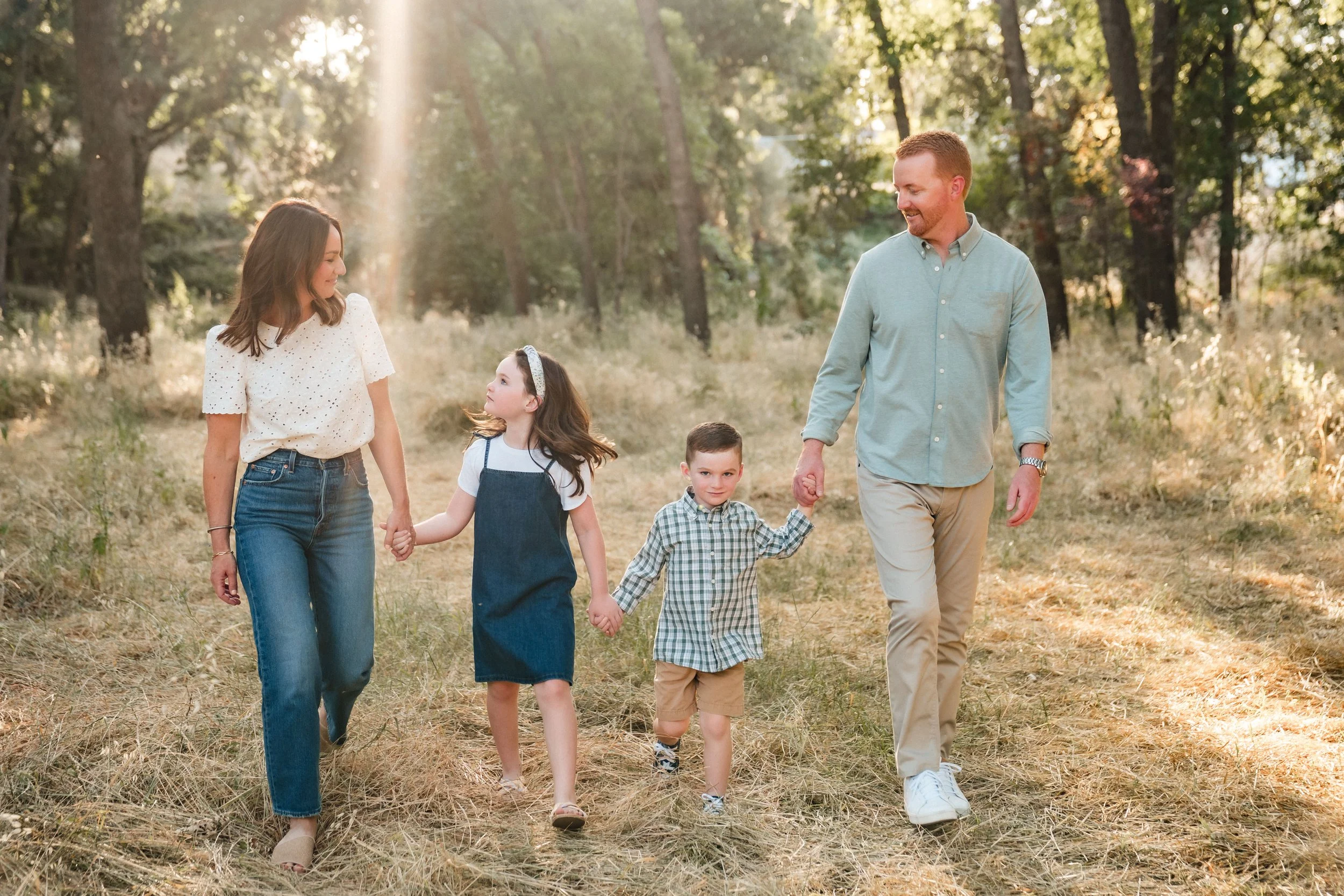 A family of five walking together through a wooded area during sunset during their family photos with Sacramento family photographer, Katherine Nicole Photography.