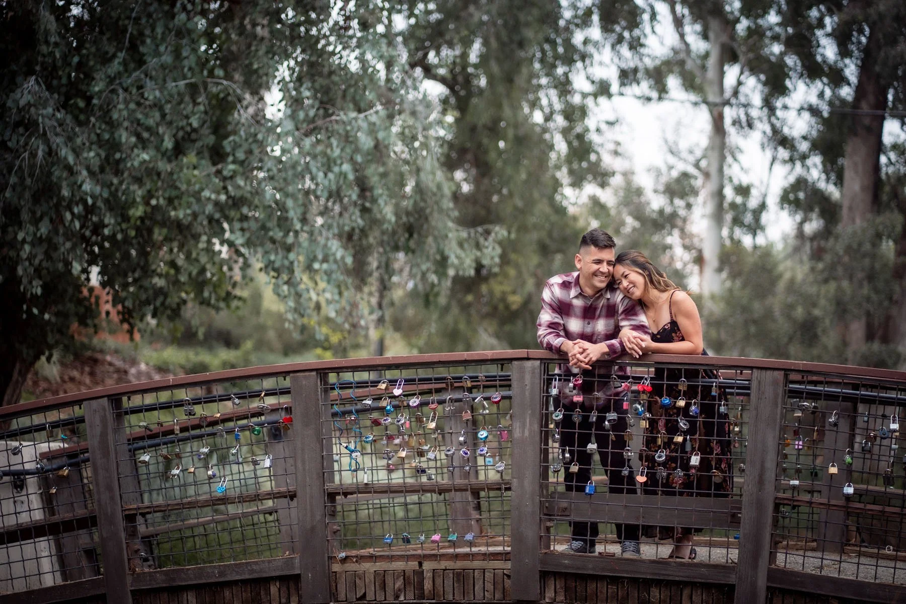 Couple stands on a bridge at the UC Davis arboretum during their engagement session photos