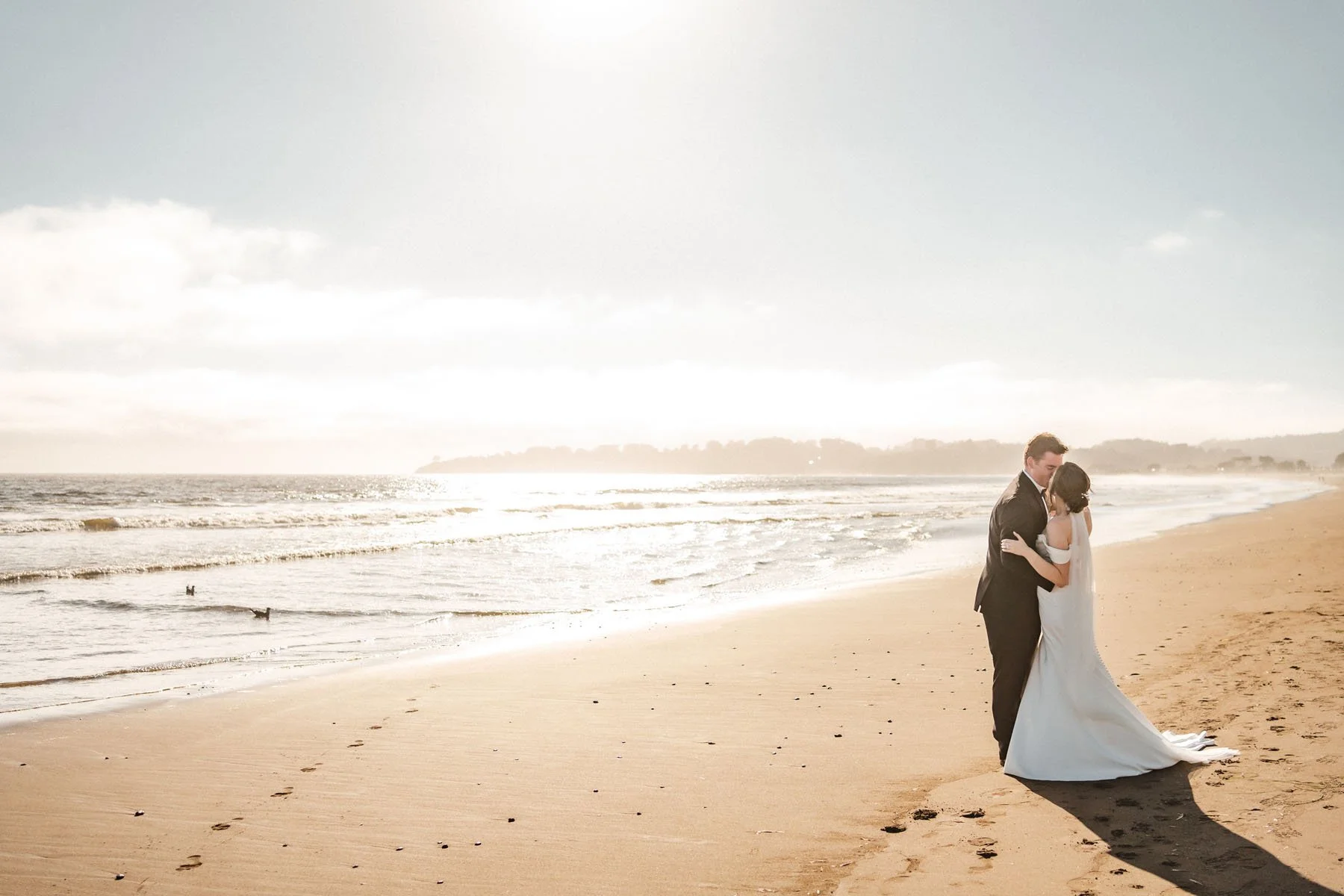 Bride and groom kiss on the beach at sunset after their Stinson Beach wedding.