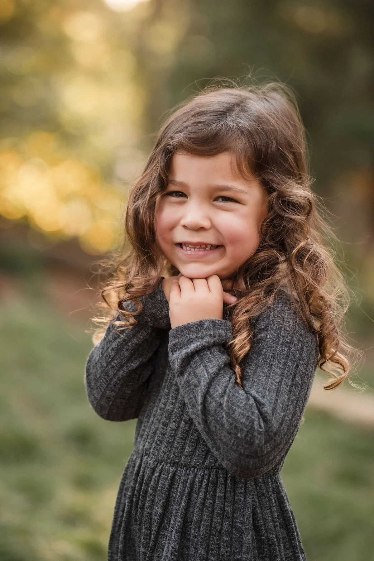 A young girl with brown curly hair smiling outdoors during autumn, taking family photos with Sacramento family photographer Katherine Nicole Photography. 