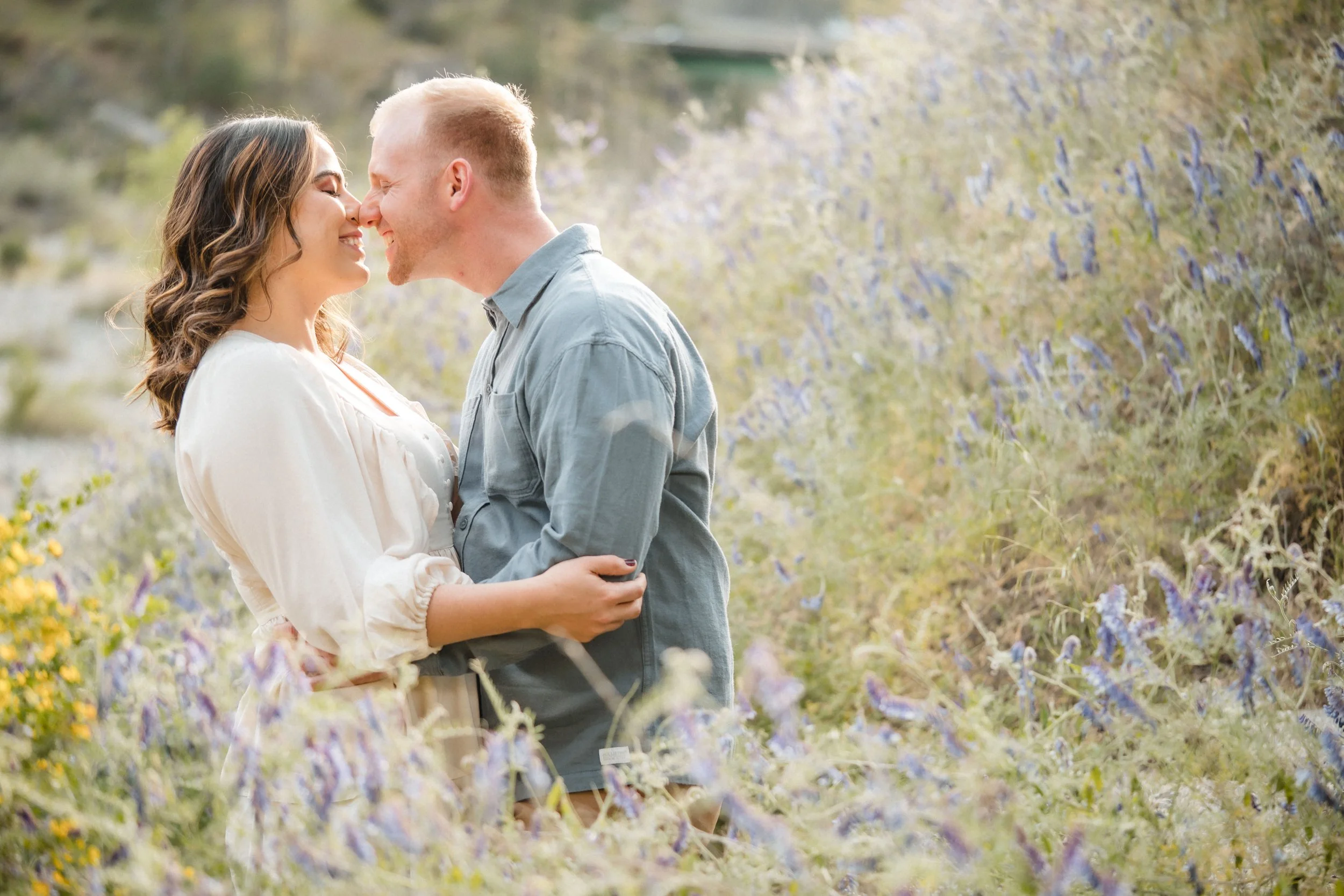 A couple kissing in a field of wildflowers during their engagement session with Katherine Nicole Photography. 