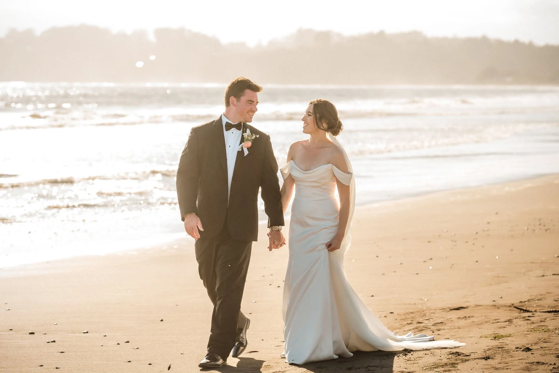 Bride and groom walk on the beach at sunset after their Stinson Beach wedding ceremony