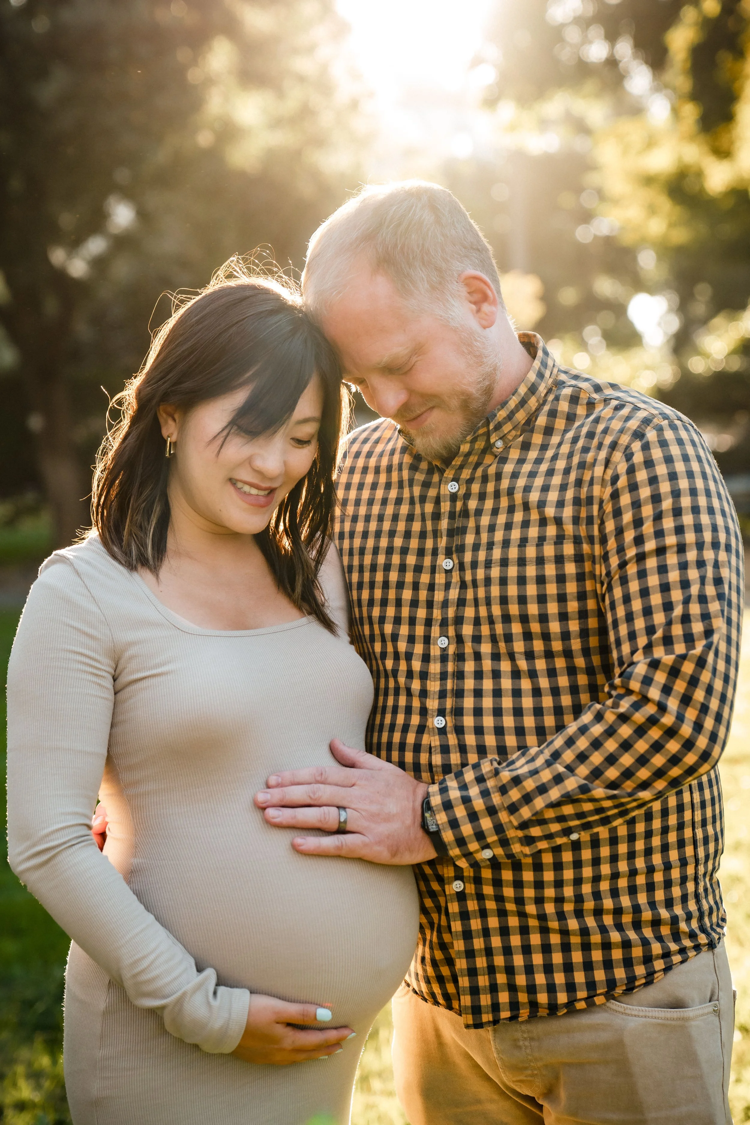 A pregnant woman with her husband, the woman is cradling her pregnant belly with her right hand, and the man's right hand is gently placed on her belly, during a photo session with Sacramento family photographer, Katherine Nicole Photography.