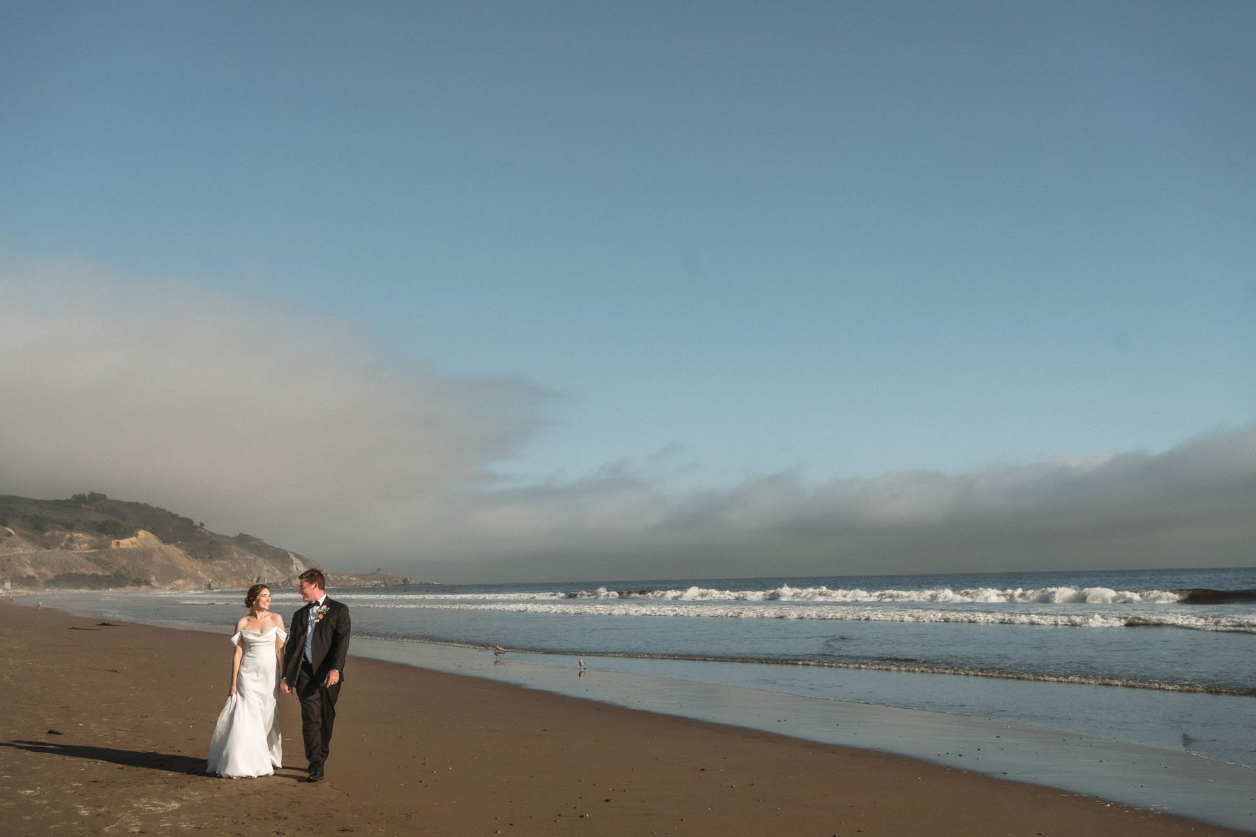 Bride and groom walk on the beach at their Stinson Beach wedding