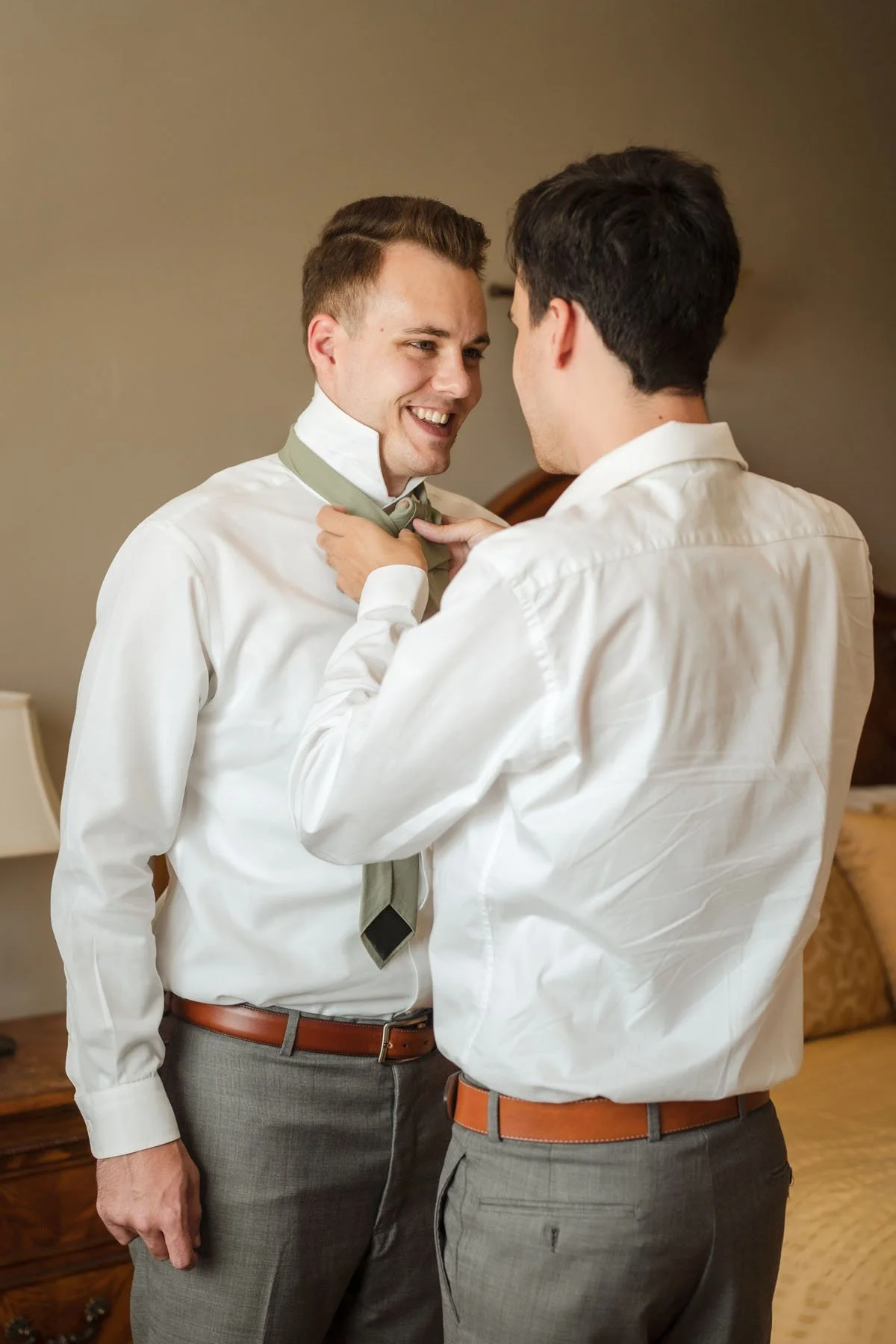 A groom and groomsmen prepare for the wedding,  with one man helping the other adjust a tie around his neck, before the ceremony at the Monte Verde Inn. Photography by Sacramento wedding photographer Katherine Nicole Photography.