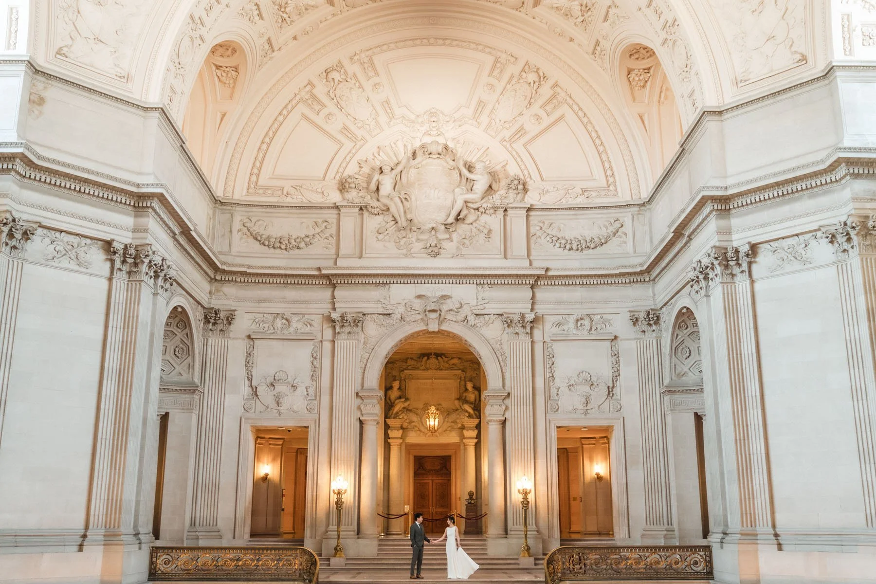 Bride and groom stand on the grand staircase at their San Francisco City Hall elopement