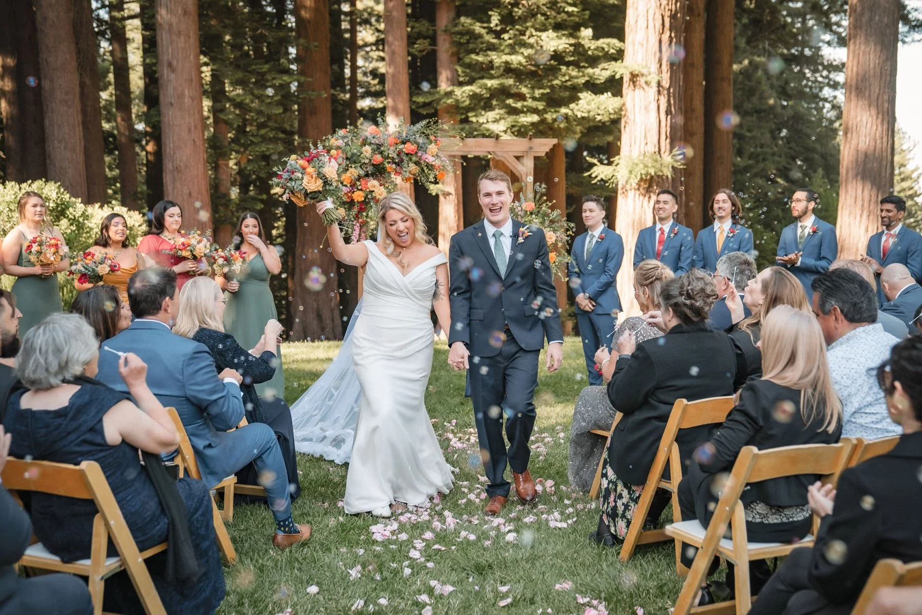 Candid photo of bride and groom walking up the aisle after their wedding ceremony surrounded by bubbles.