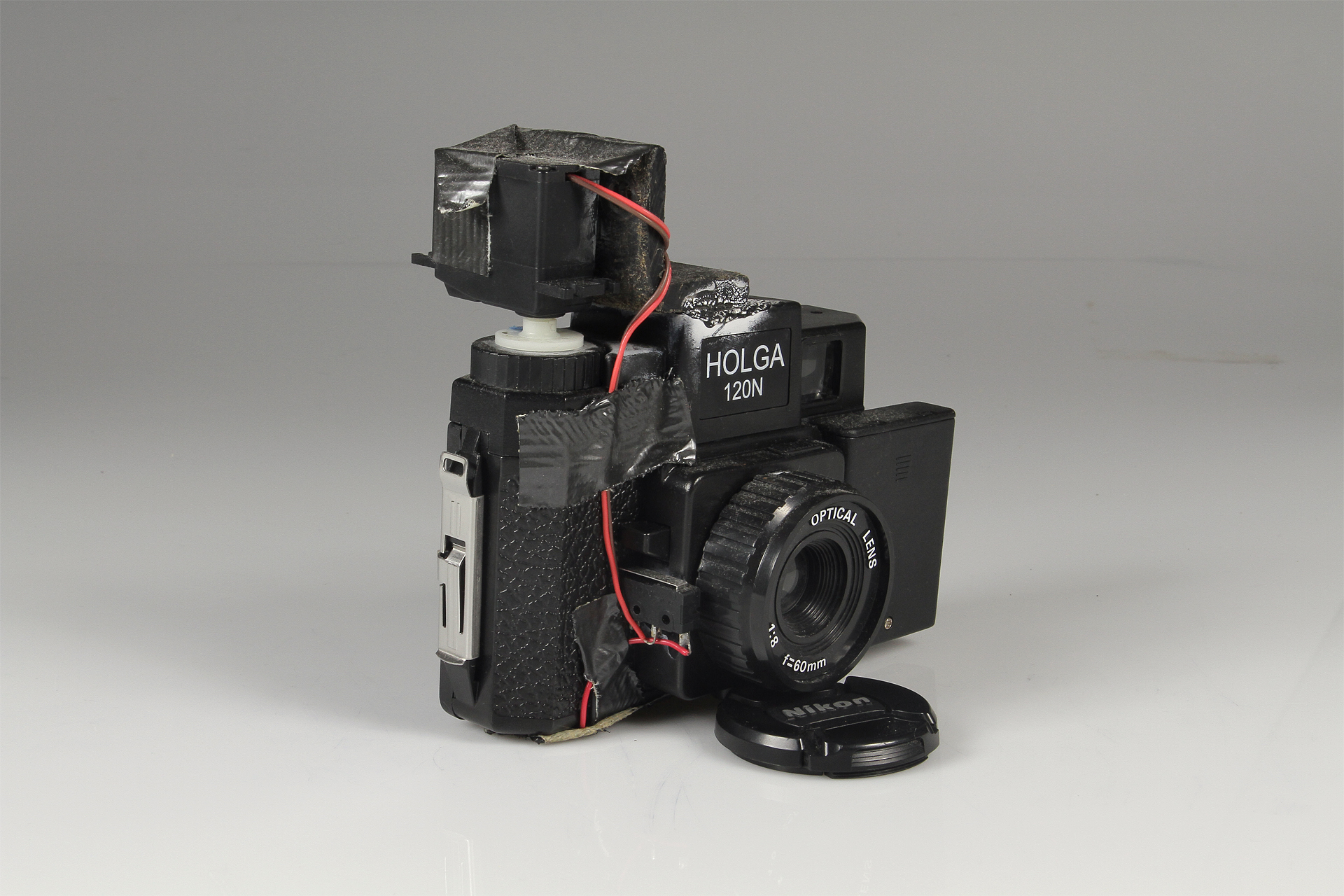   Holga Slitscan Camera  2013.&nbsp; Modified Holga for Strip Photography.&nbsp; Holga camera, modified servo motor, 3xAAA battery pack, SPST switch, plastic L bracket, black-rubberized 4x5 film (to make the slit in the camera), electrical wire, duct