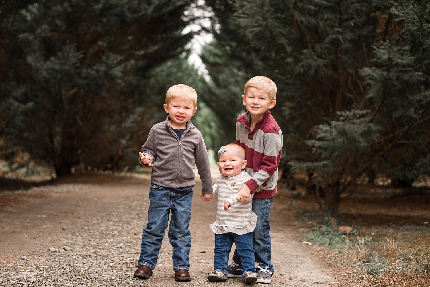 2 brothers and baby sister standing in trees Woodstock, GA