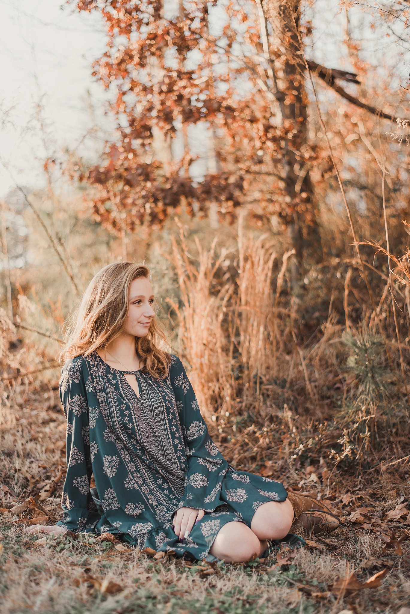 senior girl sitting in brush at golden hour