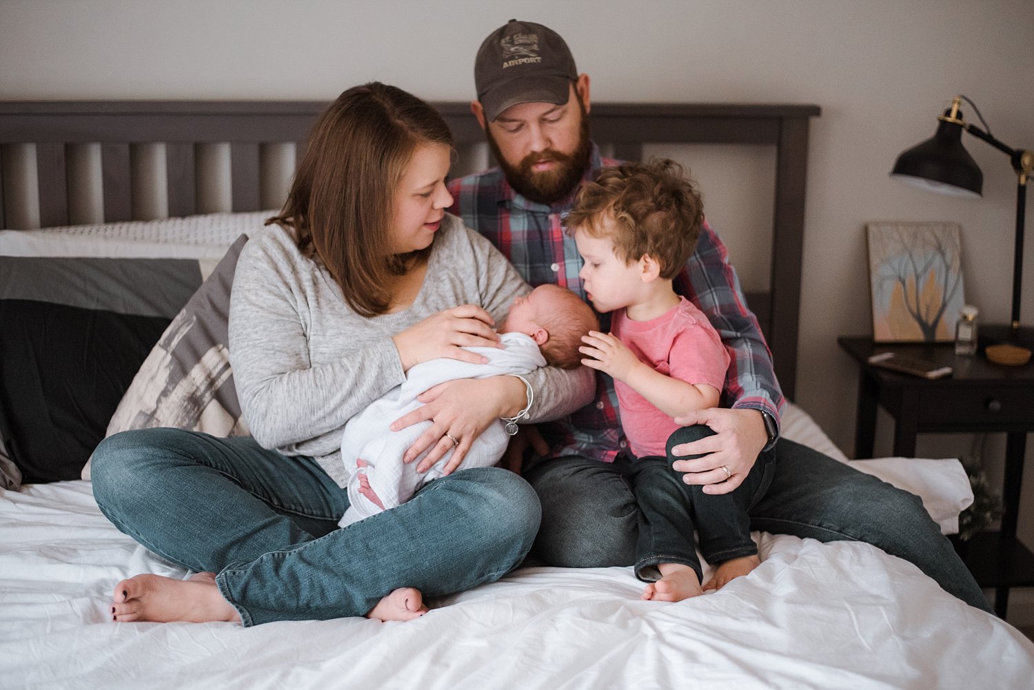 Family snuggling with newborn on bed