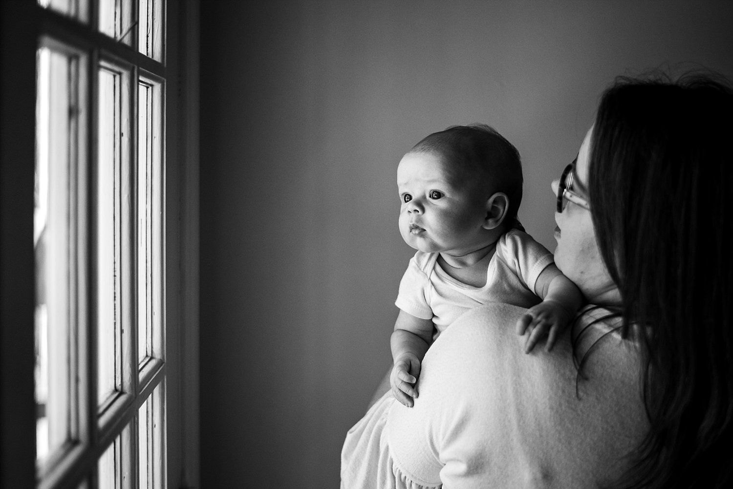 baby looking at window over moms shoulder