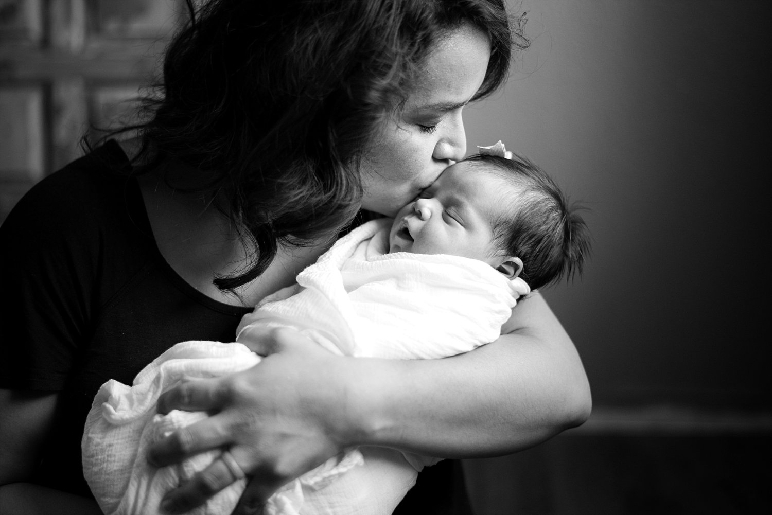 mom kissing newborn baby girl lifestyle newborn photography