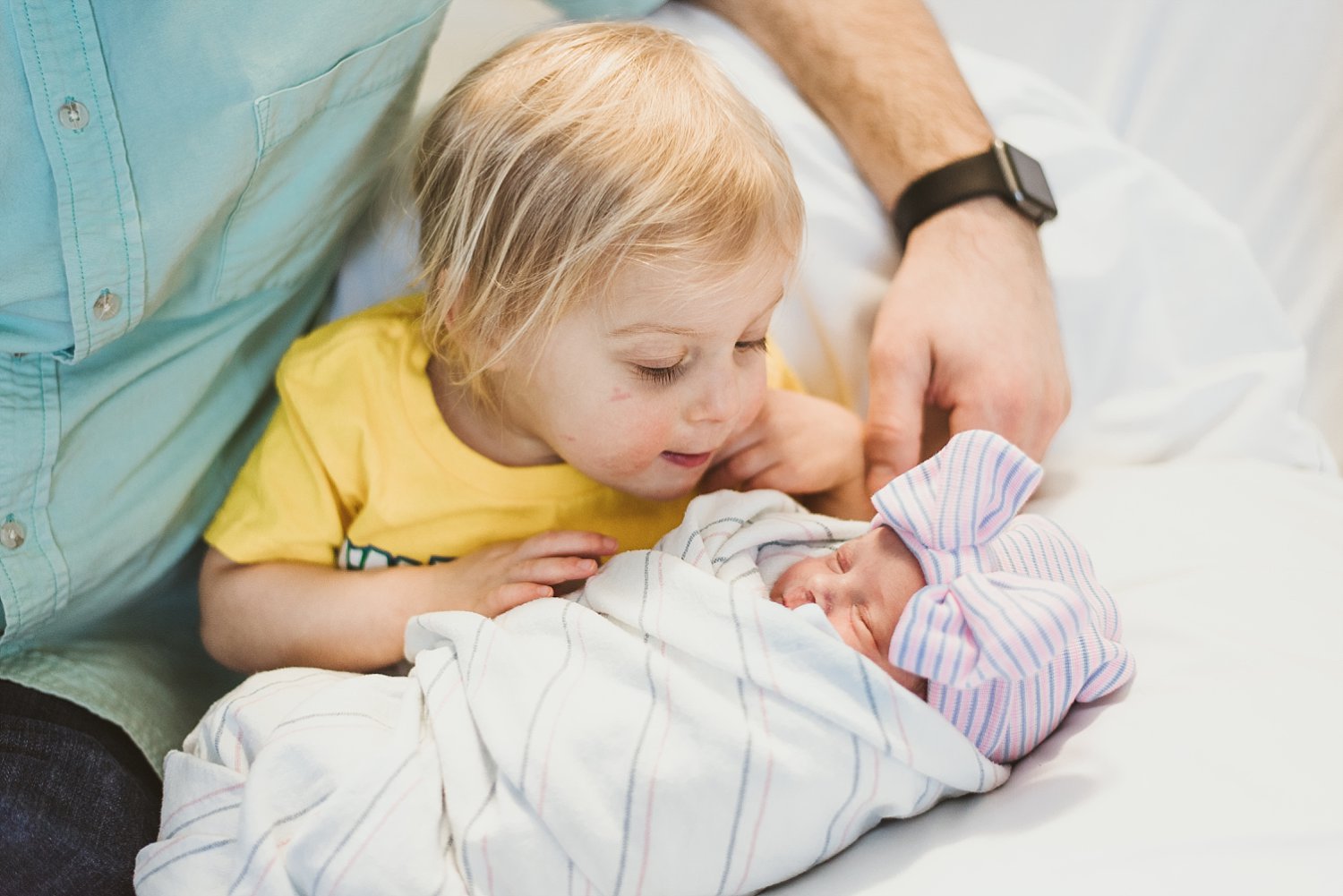 toddler girl looking closely at newborn baby sister