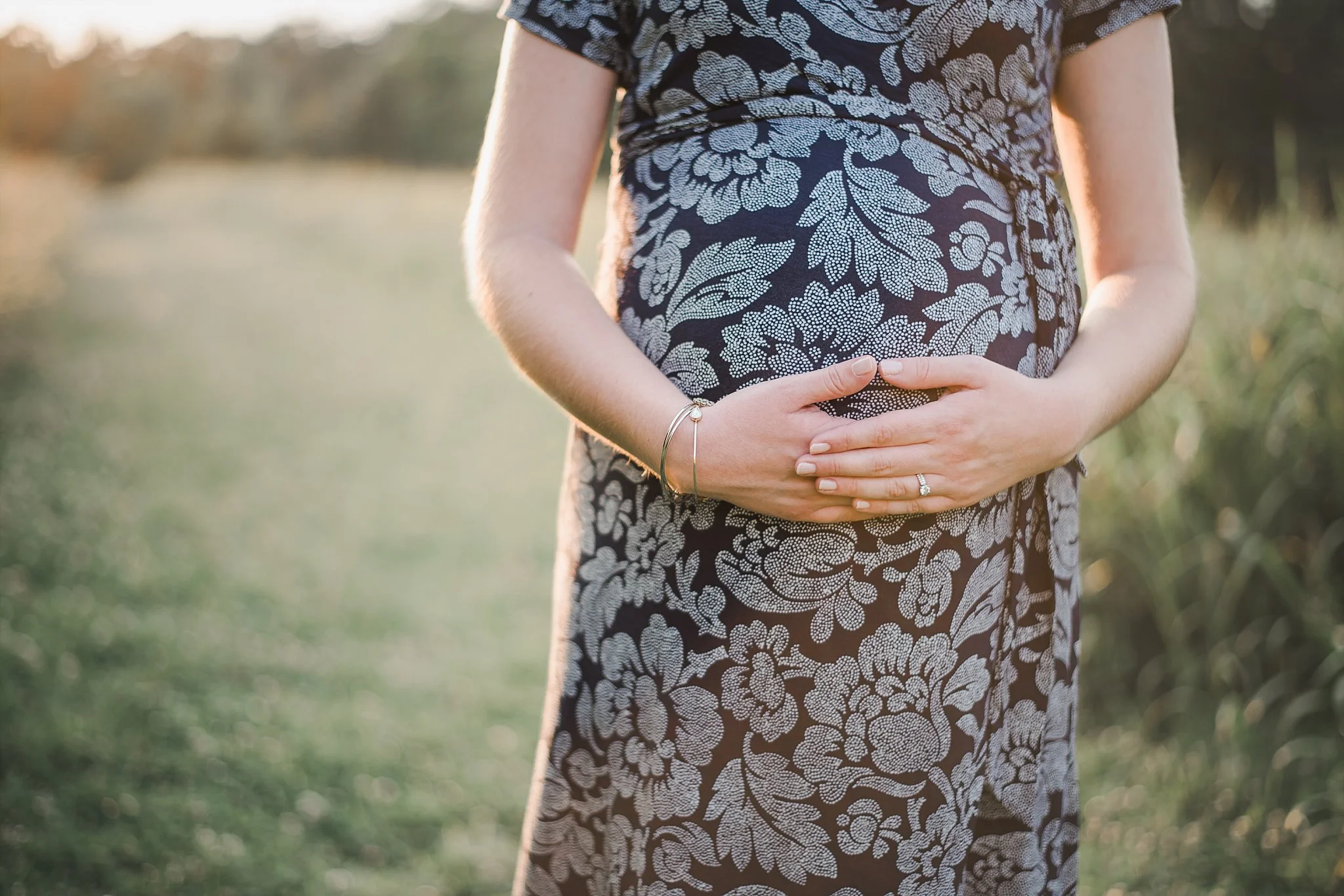 mother holding pregnant belly at sunset Green Meadows Preserve
