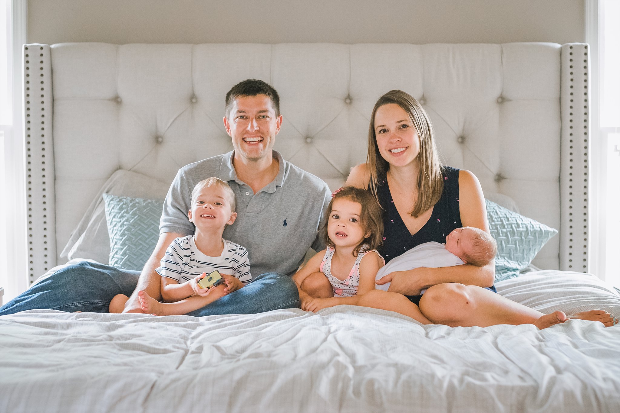 New family of five on master bed at lifestyle newborn session in Woodstock, GA