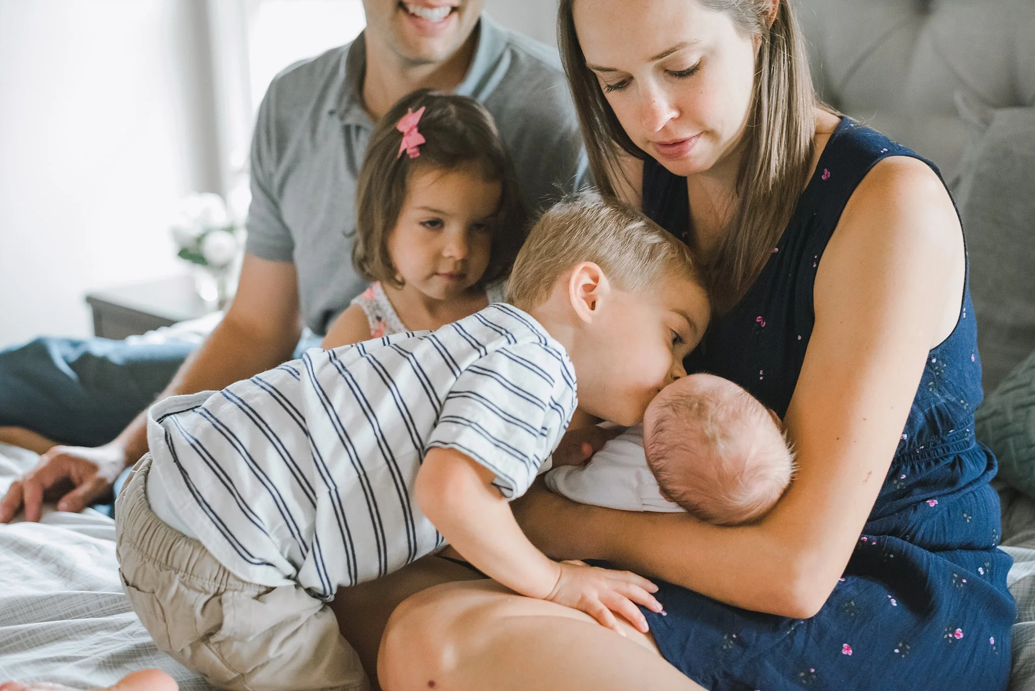 toddler boy kissing newborn baby brother