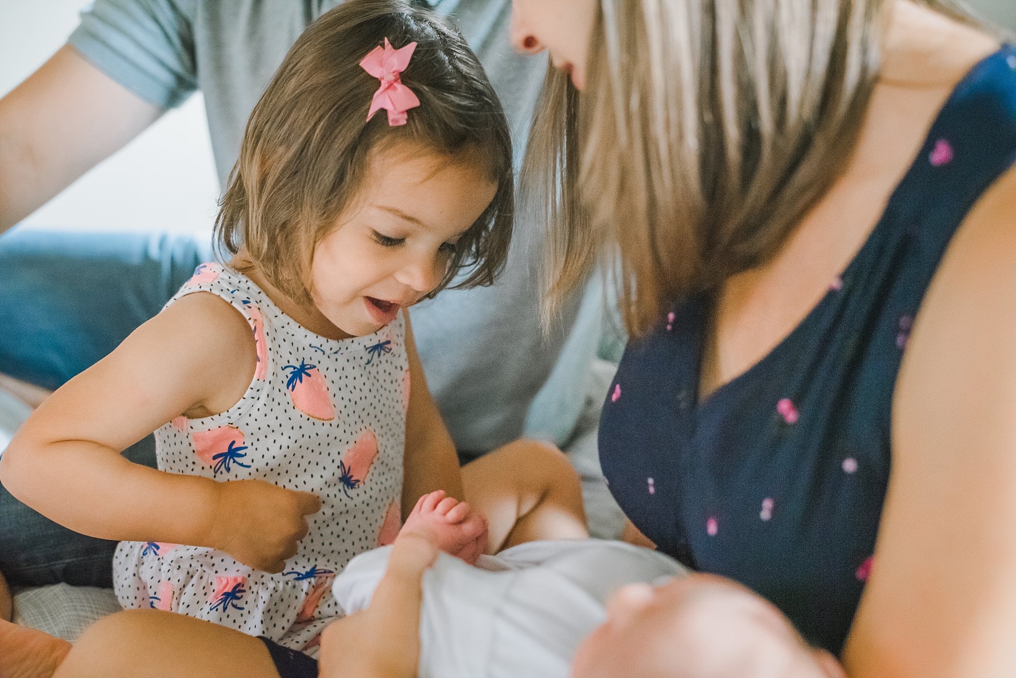 toddler girl counting newborn baby brother's toes