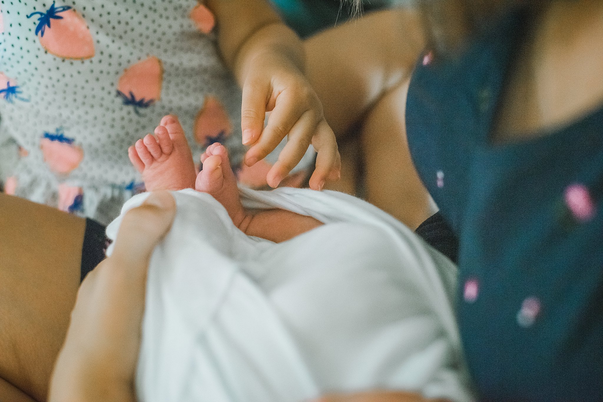 toddler sister's hands on newborn's toes